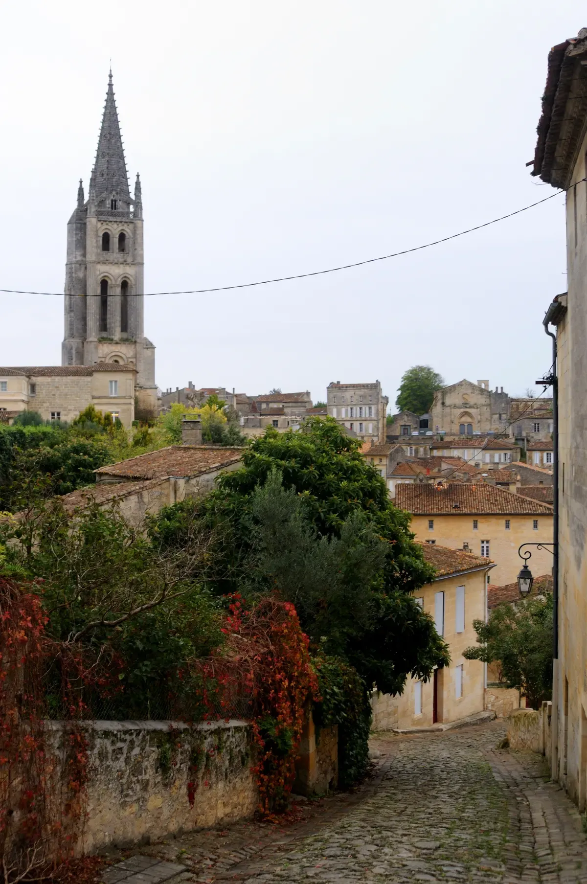 A cobbled lane climbing to the bell tower of the monolithic church in Saint-Émilion, seen on a Bordeaux wine day tour